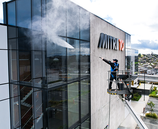 Man providing commercial building washing services to Mitre 10 building